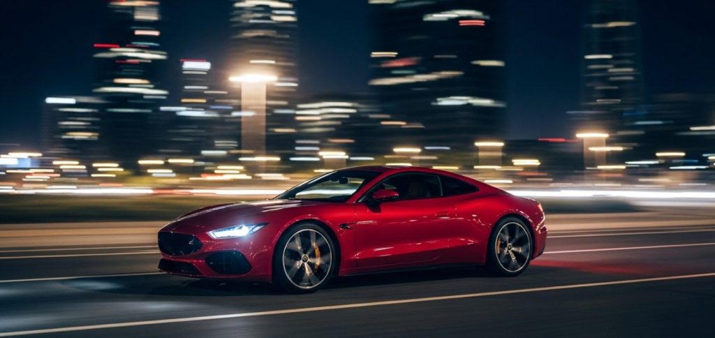 red sports car driving across city street
